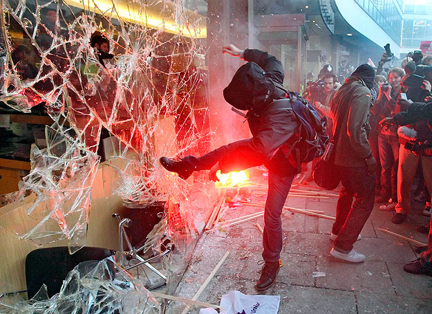 Tüntető diák berúgja a kormányzó Konzervatív Párt székházának egyik üvegablakát Londonban