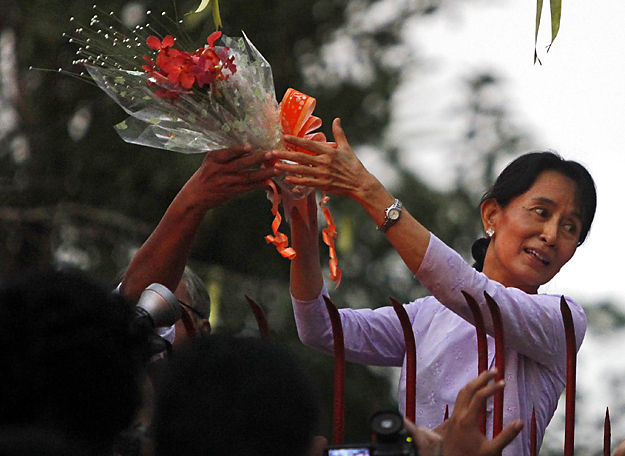 Aung Szan Szú Kji  virágot vesz át támogatóitól ranguni háza előtt