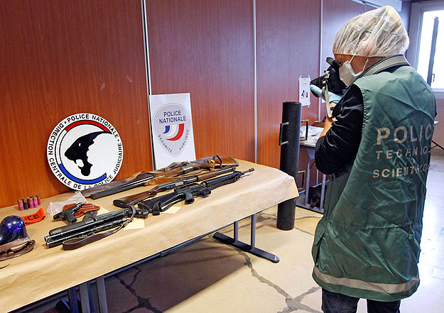 Igazságügyi szakértő fotózza a marseille-i razziákon elkobzott fegyvereket