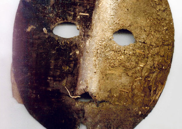 A kilógó merev szál végén egy centiméteres átmérőjű fekete üveggyöngy volt, amelyet vélhetően a maszk viselője a szájába vett és így tartotta arca előtt az álarcot