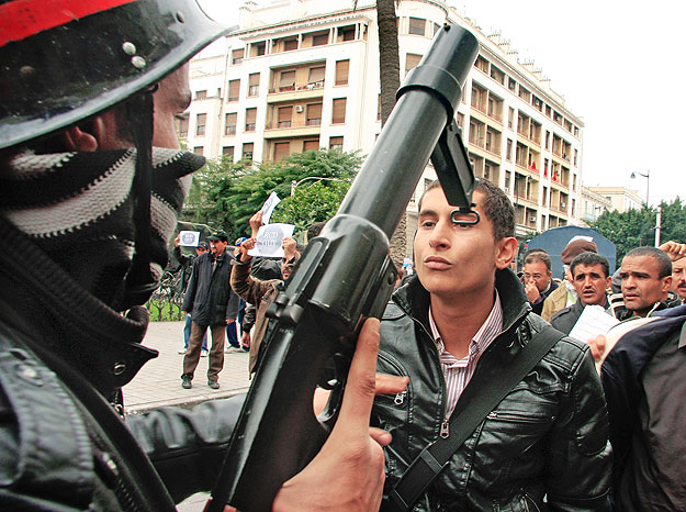 A riot policeman faces off with a protester during a demonstration in downtown Tunis January 18, 2011. Tunisia's new coalition government hit trouble on Tuesday when four ministers quit and an opposition party threatened to walk out, undermining effo