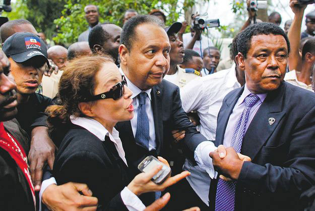 Jean-Claude Duvalier (középen) a bíróság előtt, Haiti fővárosában. Búcsút inthet a vagyonának