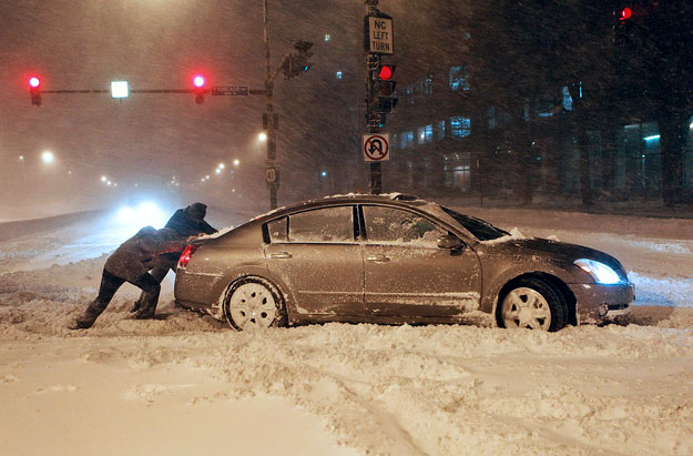 Hóban elakadt autót tolnak férfiak Chicago belvárosában