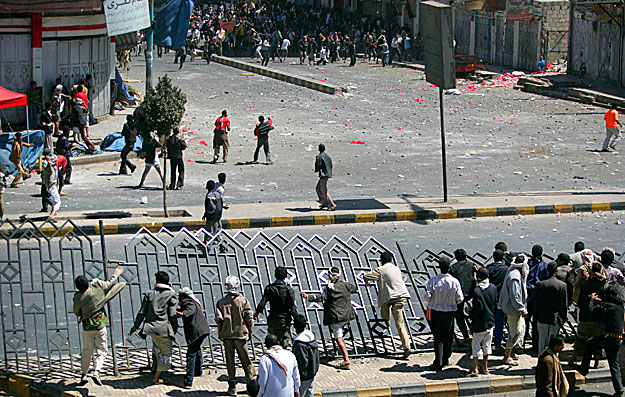 Government backers (back to the camera) break a road barrier to reach anti-government protesters during clashes in Sanaa February 17, 2011. Hundreds of Yemen government loyalists wielding batons and daggers chased off a small group of protesters tryi