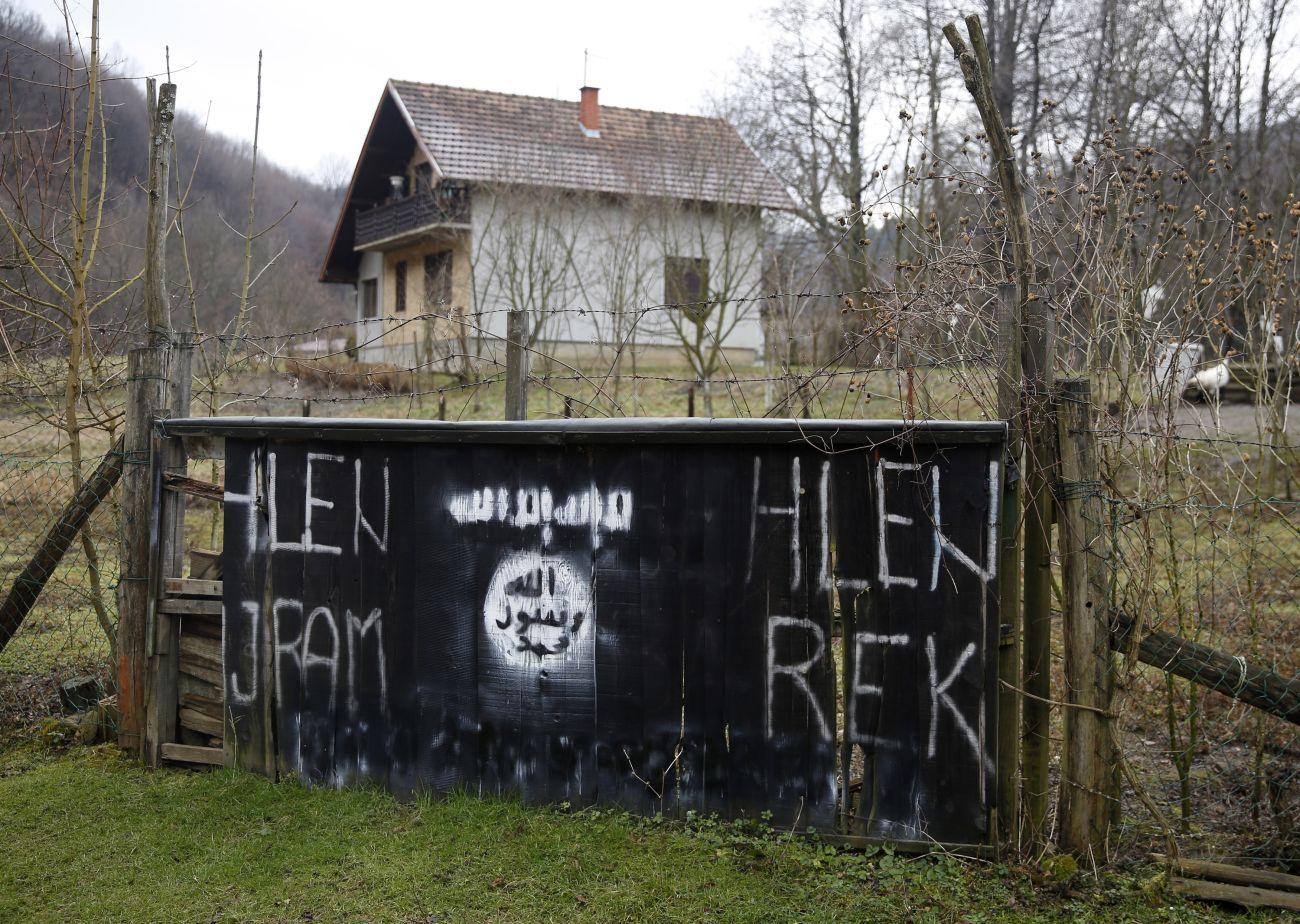 Ház egy bosznia faluban, Gornja Maocában az Iszlám Államlogójával díszített kerítés mögött